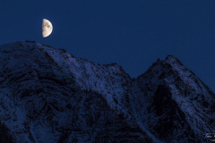 Moon rising over a snowy mountain range