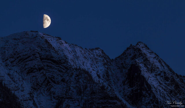 Moon rising over a snowy mountain range